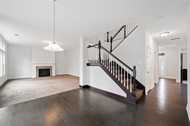 unfurnished living room featuring dark hardwood / wood-style floors and a brick fireplace