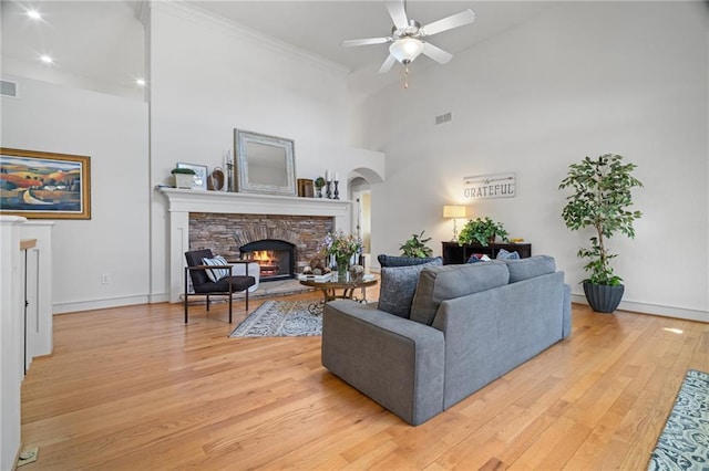 216 Crescent Moon Way, Canton, GA 30114 - living room with ceiling fan, arched walkways, light wood-style floors, visible vents, and a fireplace