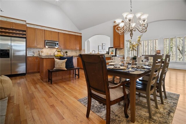 216 Crescent Moon Way, Canton, GA 30114 - dining room with an inviting chandelier, high vaulted ceiling, arched walkways, and light wood-style floors