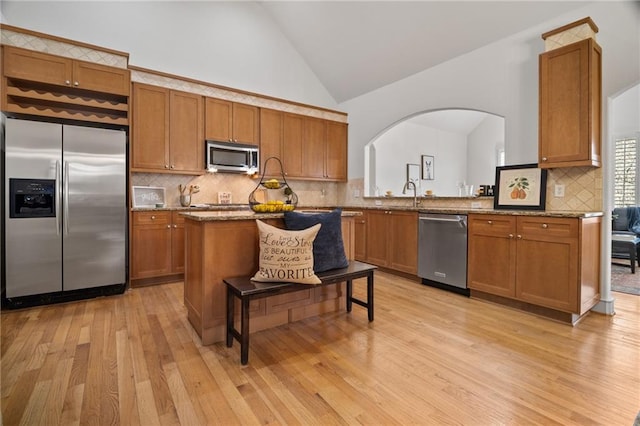 216 Crescent Moon Way, Canton, GA 30114 - kitchen featuring arched walkways, stainless steel appliances, light wood-style floors, and brown cabinets