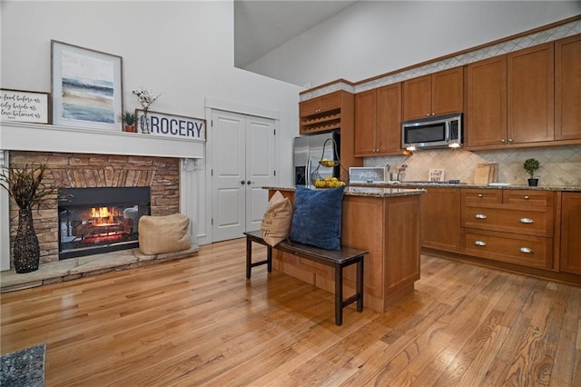 216 Crescent Moon Way, Canton, GA 30114 - kitchen featuring a kitchen breakfast bar, light wood-style flooring, appliances with stainless steel finishes, and brown cabinetry
