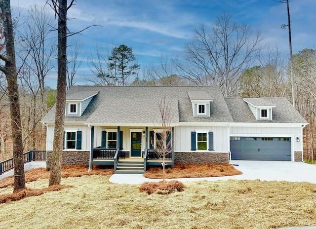 view of front facade with a porch, an attached garage, concrete driveway, stone siding, and board and batten siding