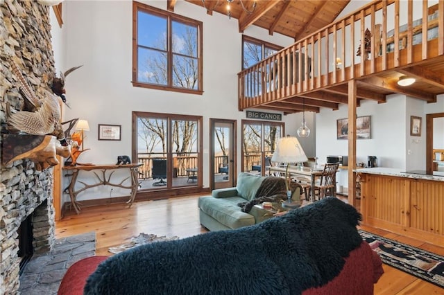 living area featuring beam ceiling, a fireplace, wood ceiling, high vaulted ceiling, and hardwood / wood-style floors