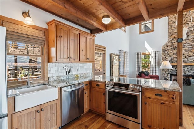 kitchen featuring beam ceiling, stainless steel appliances, wood ceiling, a sink, and a peninsula