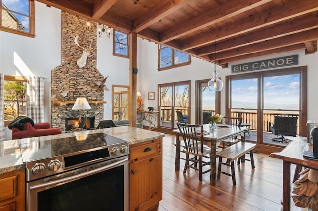 kitchen featuring wood-type flooring, a fireplace, stainless steel electric stove, and brown cabinetry