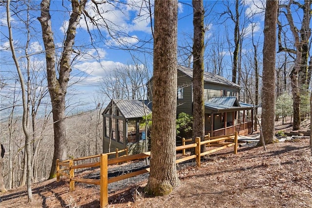 view of home's exterior with a porch, metal roof, and fence