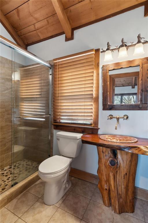 bathroom with vaulted ceiling with beams, tile patterned flooring, and toilet