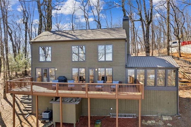 rear view of house featuring cooling unit, metal roof, a chimney, and a wooden deck