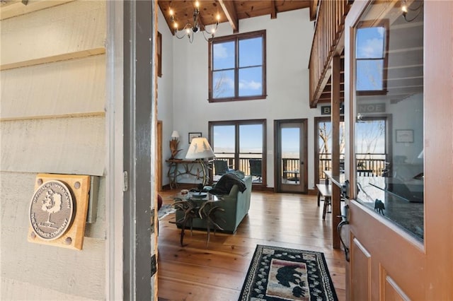 foyer entrance with an inviting chandelier, wood-type flooring, a high ceiling, and plenty of natural light