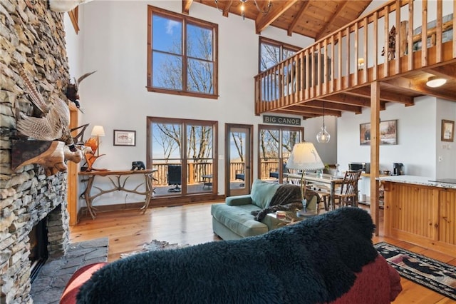 living area featuring hardwood / wood-style floors, beam ceiling, a fireplace, and wood ceiling