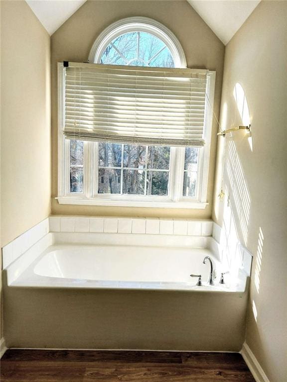 bathroom with a washtub and vaulted ceiling