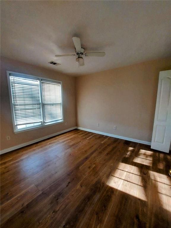 spare room with dark hardwood / wood-style flooring and ceiling fan