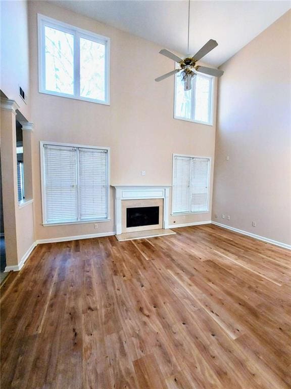 unfurnished living room with ceiling fan, a high ceiling, and hardwood / wood-style flooring