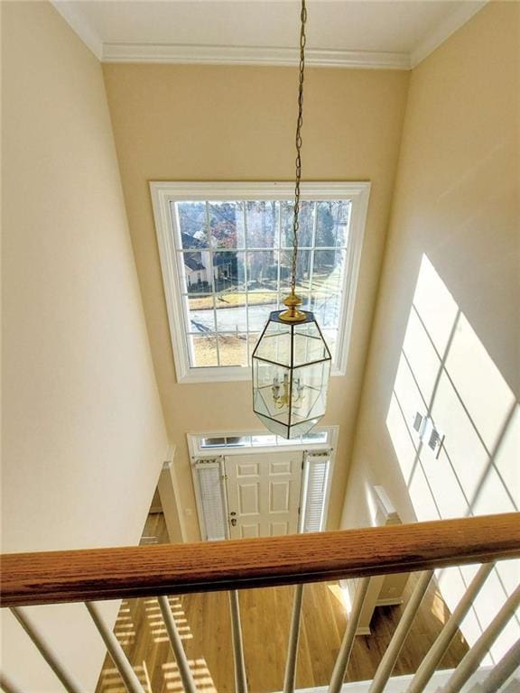 staircase featuring an inviting chandelier and crown molding