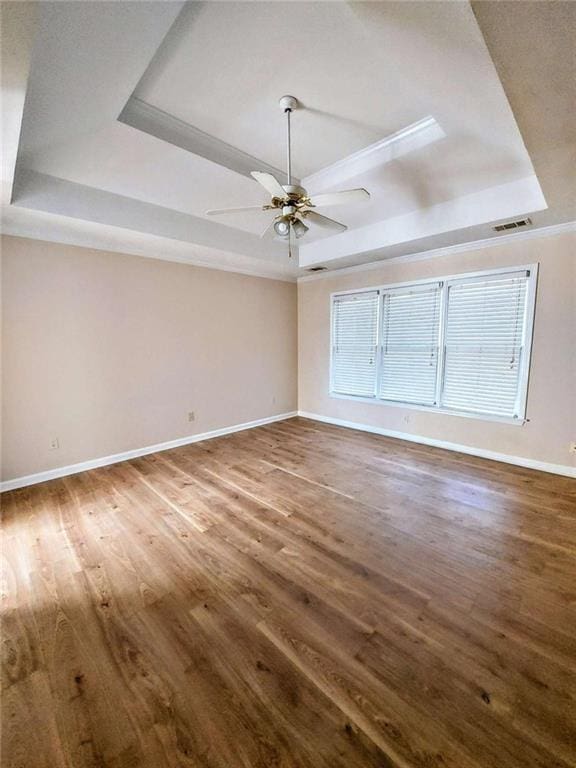 empty room with a tray ceiling, ceiling fan, and hardwood / wood-style flooring