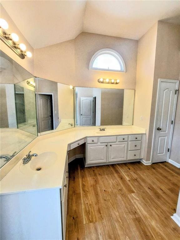 bathroom featuring vanity, wood-type flooring, and high vaulted ceiling