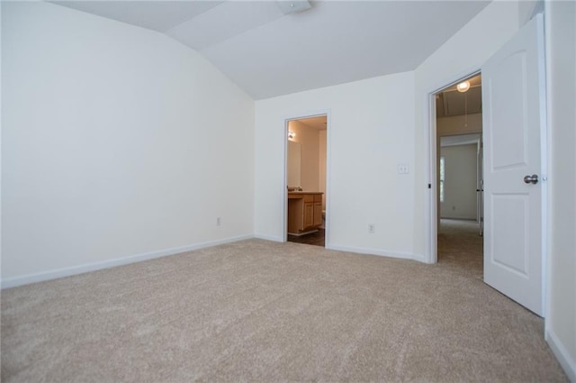 unfurnished bedroom with lofted ceiling, attic access, light carpet, and baseboards