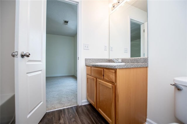 full bathroom with baseboards, visible vents, toilet, wood finished floors, and vanity