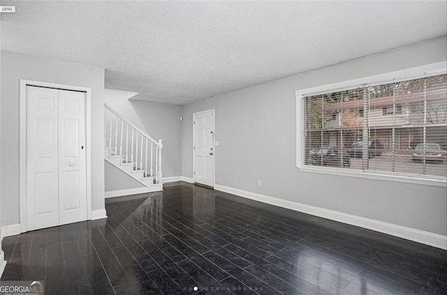 unfurnished living room featuring dark hardwood / wood-style floors and a textured ceiling