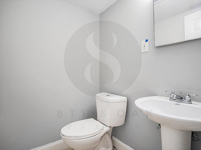 bathroom with sink, toilet, and a textured ceiling