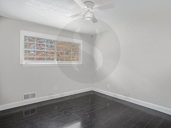 unfurnished room featuring hardwood / wood-style flooring, ceiling fan, and a textured ceiling