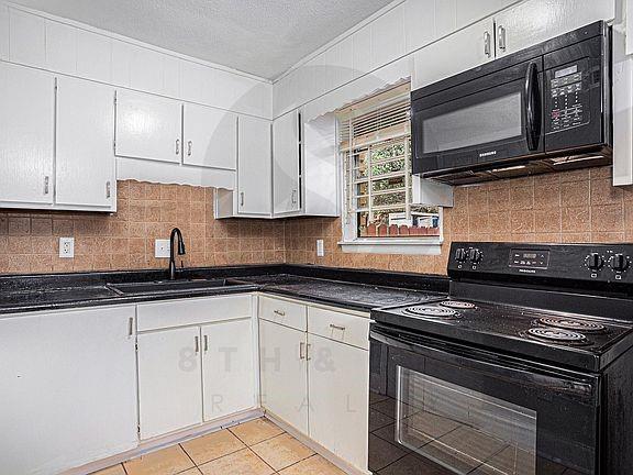 kitchen featuring backsplash, white cabinets, sink, and black appliances