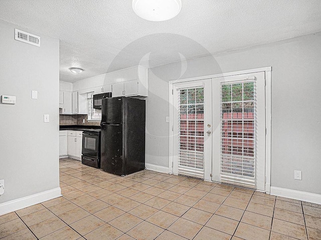 kitchen featuring light tile patterned flooring, white cabinets, a textured ceiling, and black appliances