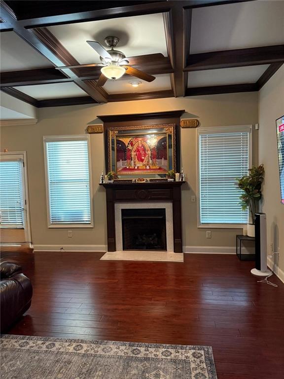 living area featuring baseboards, coffered ceiling, wood-type flooring, a fireplace, and a ceiling fan