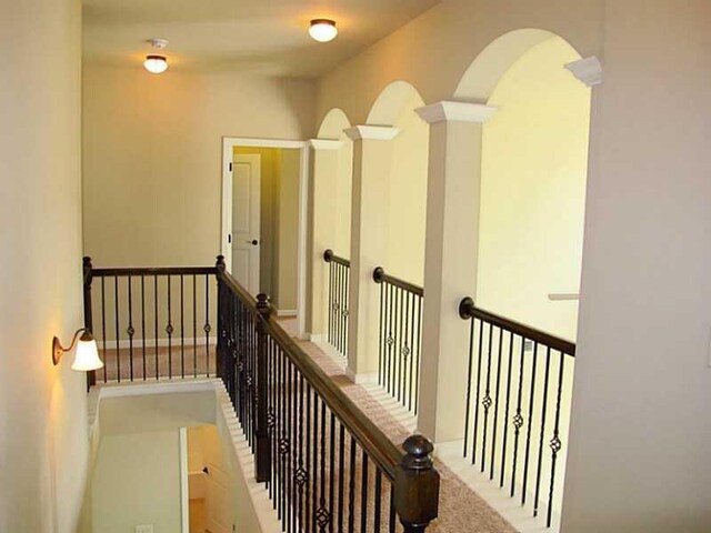 corridor featuring arched walkways and an upstairs landing