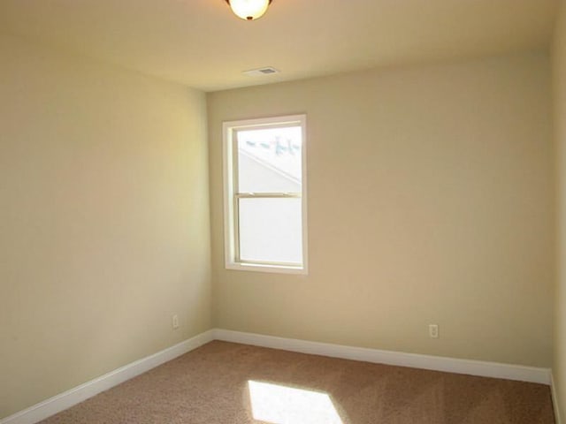 spare room featuring light colored carpet and baseboards