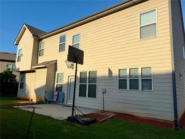 back of house with a patio and a lawn