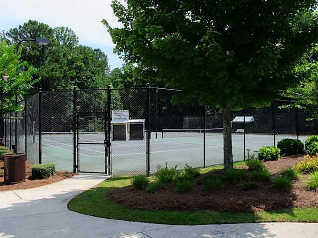 view of tennis court with a gate and fence