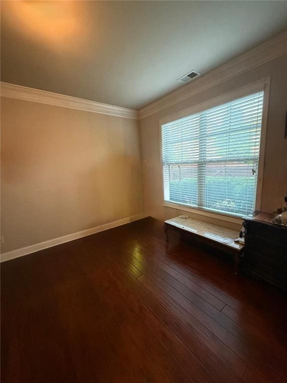 unfurnished room with dark wood-style floors, ornamental molding, and baseboards