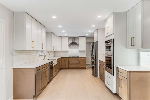 kitchen featuring wall chimney exhaust hood, light wood-type flooring, light countertops, and stainless steel appliances