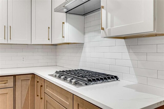 kitchen featuring stainless steel gas cooktop, tasteful backsplash, extractor fan, and white cabinets