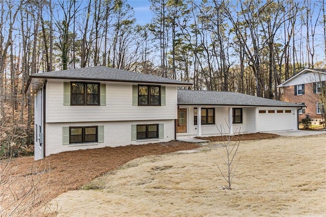 tri-level home with brick siding, driveway, an attached garage, and roof with shingles