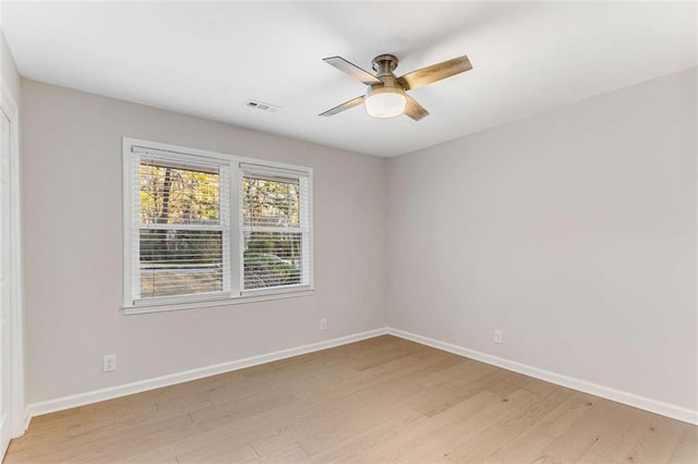 unfurnished room with a ceiling fan, visible vents, light wood-style flooring, and baseboards