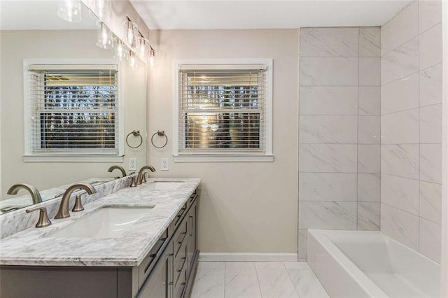 bathroom with marble finish floor, double vanity, a sink, and baseboards