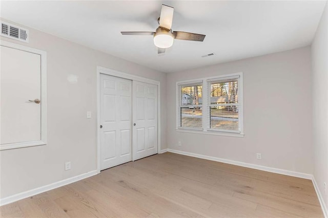 unfurnished bedroom featuring light wood-style flooring, a closet, visible vents, and baseboards