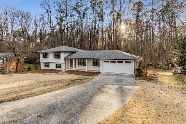 split level home featuring a garage, roof with shingles, and driveway