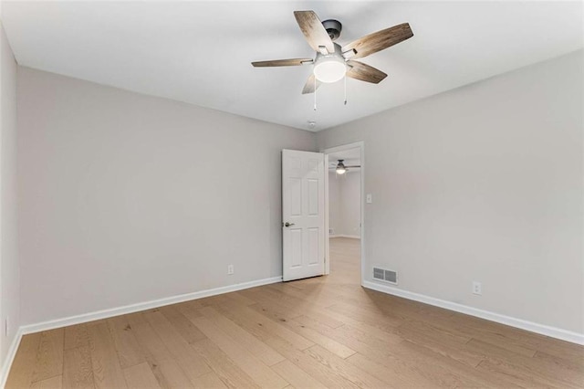 unfurnished room with light wood finished floors, baseboards, visible vents, and a ceiling fan