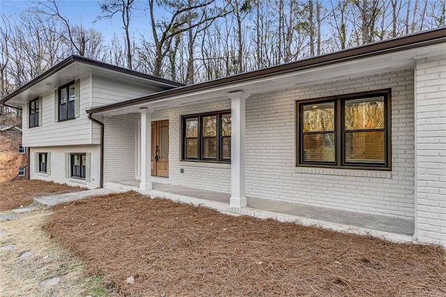 exterior space featuring covered porch and brick siding