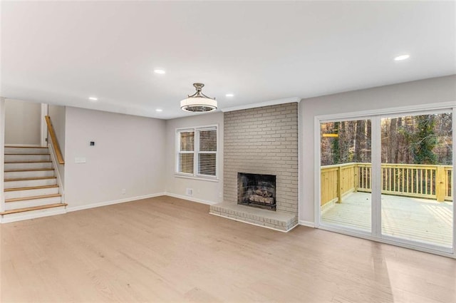 unfurnished living room featuring recessed lighting, wood finished floors, baseboards, stairs, and a brick fireplace