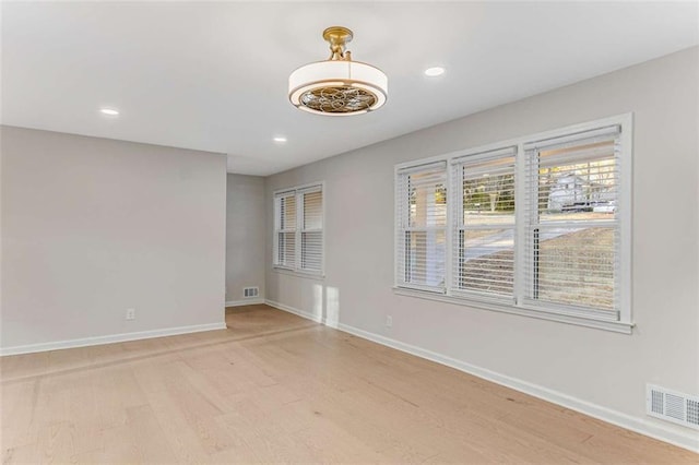 unfurnished room with visible vents, light wood-style flooring, and baseboards