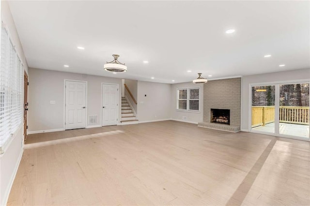 unfurnished living room with stairs, light wood finished floors, a fireplace, and recessed lighting