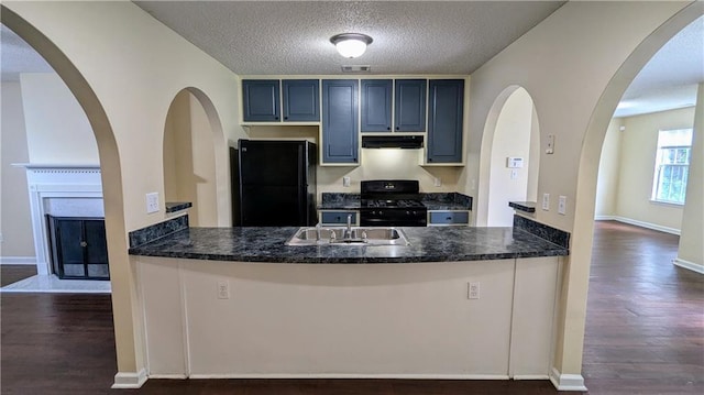 4707 Golod Way, Lithonia, GA 30038 - kitchen with freestanding refrigerator, gas stove, under cabinet range hood, a peninsula, and dark wood finished floors