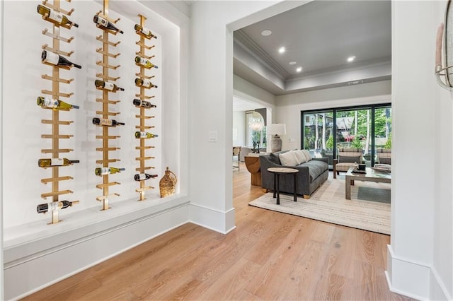 wine area with wood finished floors, baseboards, ornamental molding, and recessed lighting
