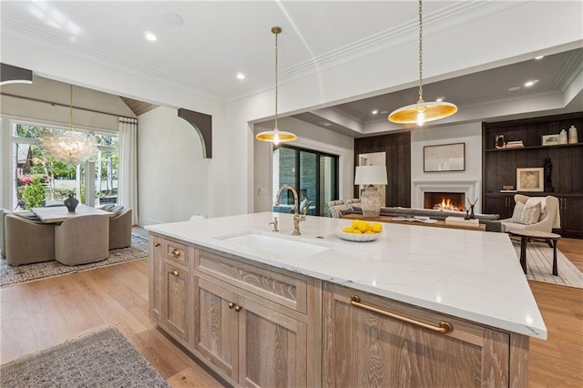 kitchen featuring open floor plan, light stone counters, a sink, and a lit fireplace