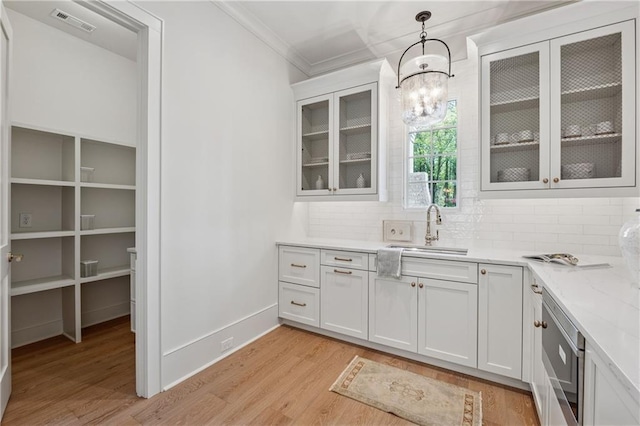 bar with a sink, visible vents, decorative backsplash, and light wood finished floors