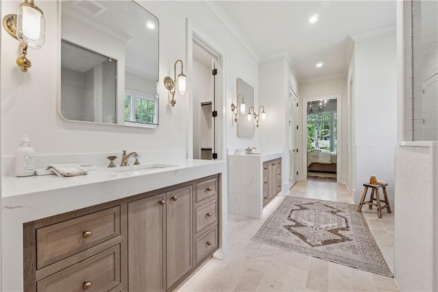 full bath featuring two vanities, ensuite bath, a sink, and ornamental molding